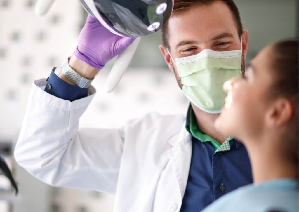 Dentist examining a patient's tooth before treatment, illustrating the dental visit involved in how long a tooth filling takes.