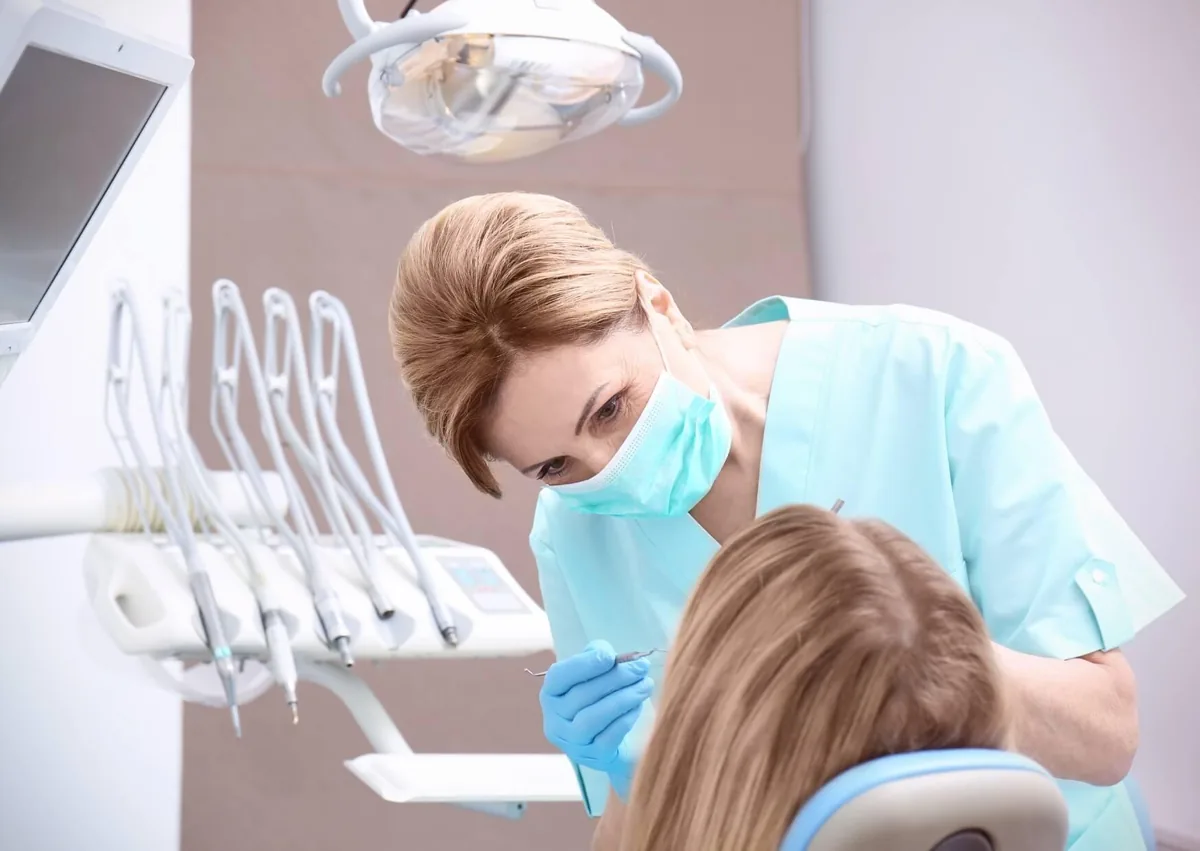 Dentist examining a patient's teeth during a dental checkup to assess oral health and the number of natural teeth in the mouth.