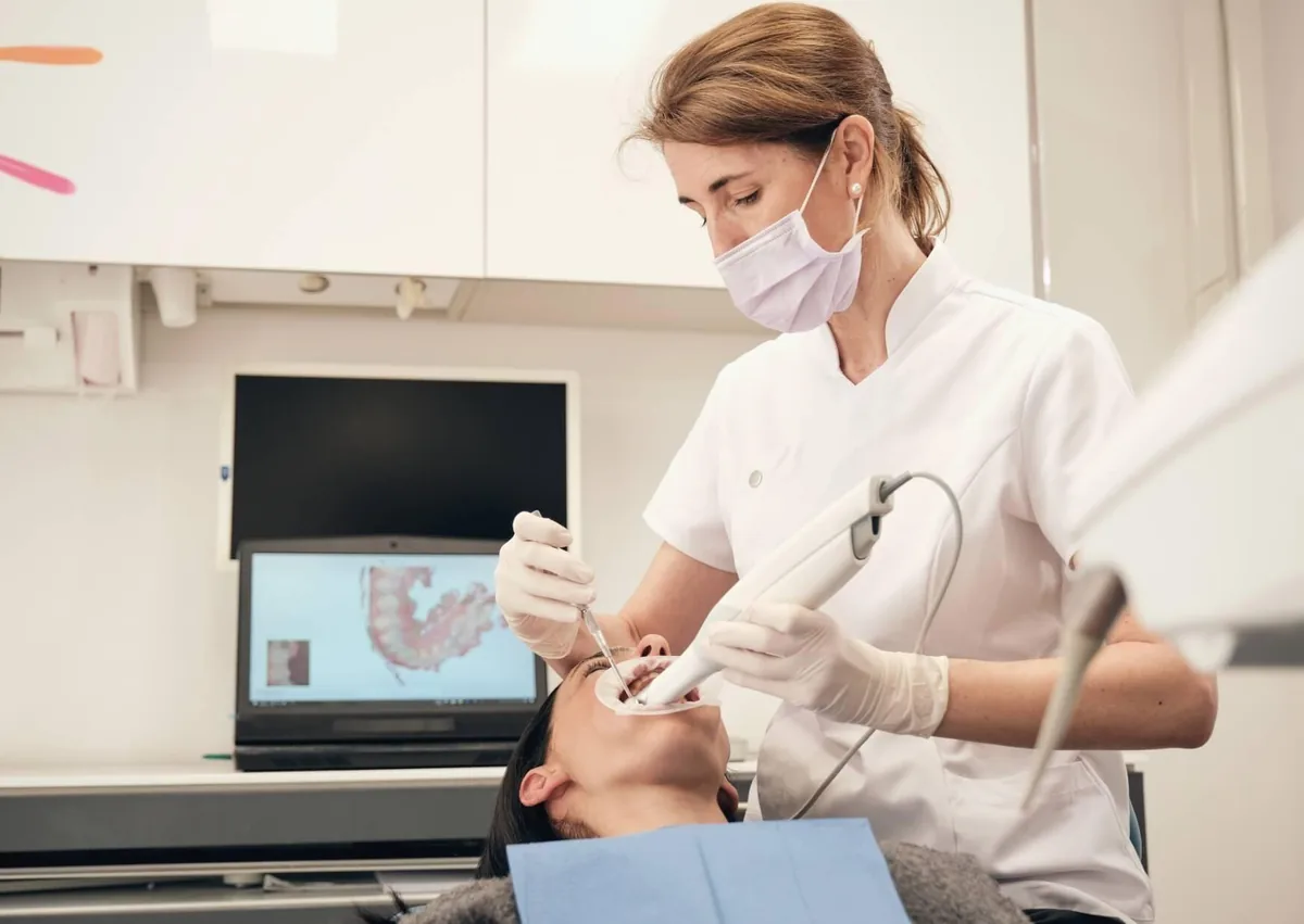 Dentist examining a patient's teeth during a consultation to evaluate dental crown options, materials, and treatment costs.